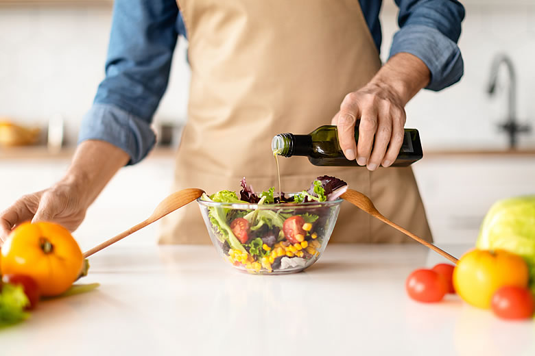 Man Pouring Olive Oil on Salad