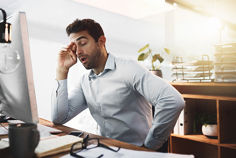 Man Yawning at Desk